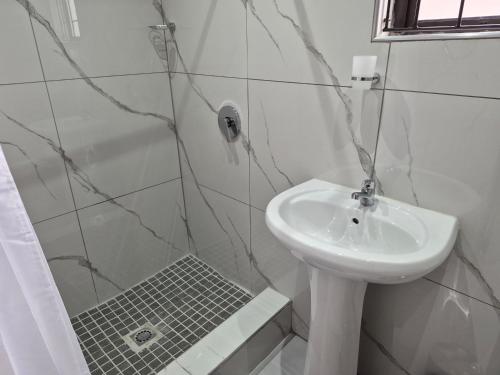 a white bathroom with a sink and a shower at Sweetwaters Guest House in Estcourt