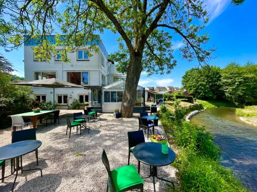 a building with tables and chairs next to a river at Boutiquehotel B&B the SJinn in Schin op Geul