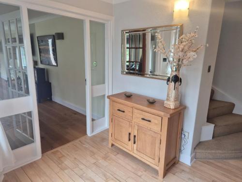 a hallway with a vase of flowers on a wooden cabinet at Three Trees Cottage in Lochmaben