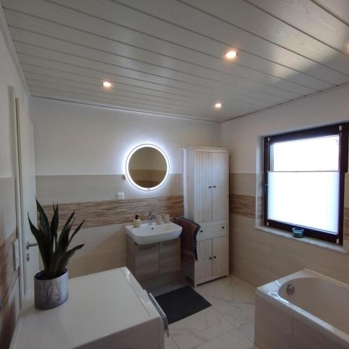 a bathroom with a sink and a tub and a window at Ferienhaus Feldbrise in Gottesgabe