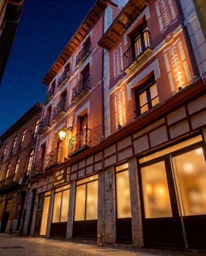 a tall building with windows on a street at night at Feeling Home Suites&Rooms in León