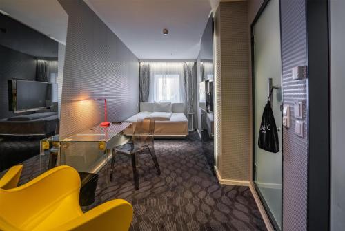 ein Hotelzimmer mit einem Bett, einem Schreibtisch und gelben Stühlen in der Unterkunft Magic Hotel Bergen City Center, a member of Radisson Individuals in Bergen