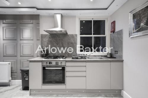 a kitchen with a stove and a sink and a window at Hackney Suites - En-suite rooms & amenities in London