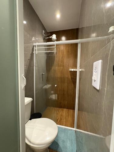 a bathroom with a toilet and a glass shower at Pousada - Aconchego da tia Zeni in Mangaratiba