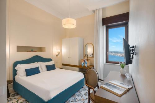 a bedroom with a bed and a desk and a window at Experience Boutique Hotel - Villa Cimmino in Castellammare di Stabia
