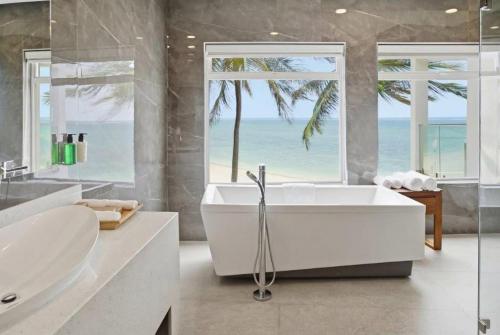 バンブリにあるBamburi Beach Hotelのバスタブとビーチのある白いバスルーム