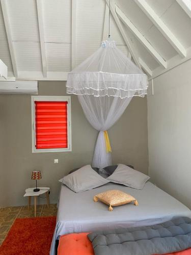 a bedroom with a white bed with a red window at Logement entier, Bungalow ou T2 in Sainte-Rose
