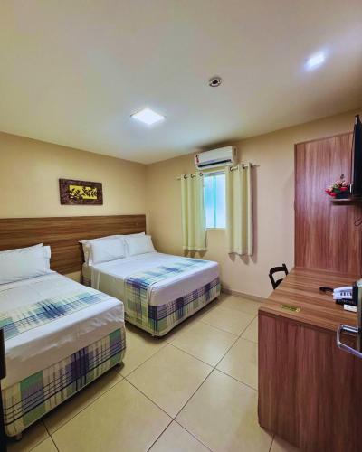 a hotel room with two beds and a television at Moda Center Hotel in Santa Cruz do Capibaribe