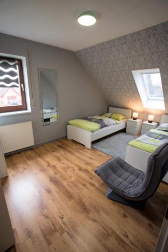 a room with two beds and a chair in it at Zum Käutzchen 120qm Ferienhaus 8 Personen 4 Schlafzimmer in Nossentiner Hütte