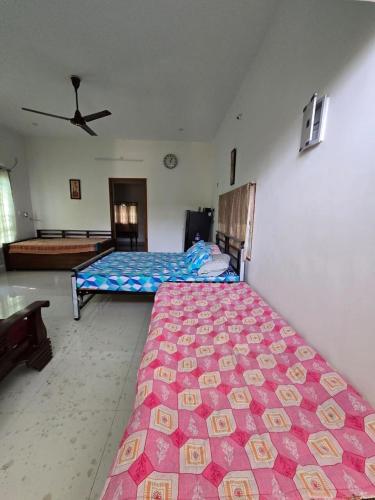 a bedroom with two beds and a ceiling fan at Green Heavan Farm in Sadras