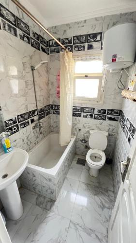 a bathroom with a tub and a toilet and a sink at Spring house in Qaryat Shākūsh