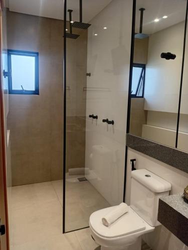 a bathroom with a toilet and a glass shower at Pousada Varandas do Lago in Capitólio