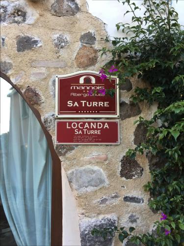 a sign for a restaurant on a stone wall at Albergo Diffuso Mannois in Orosei