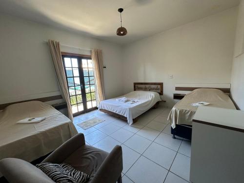 a room with two beds and a chair in it at Pousada Dunas da guarda in Guarda do Embaú