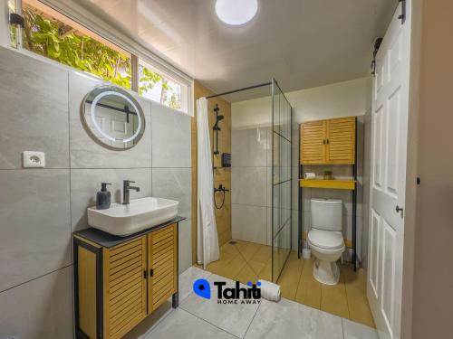 a bathroom with a sink and a toilet and a mirror at Moorea Temae Surf Tiny House in Teavaro