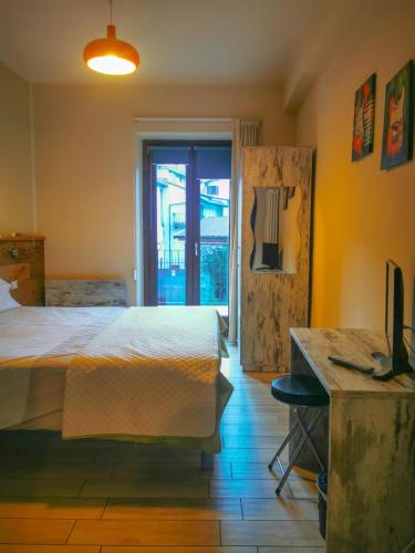 a bedroom with a bed and a desk and a television at Locanda Ponte Rosa in Garessio