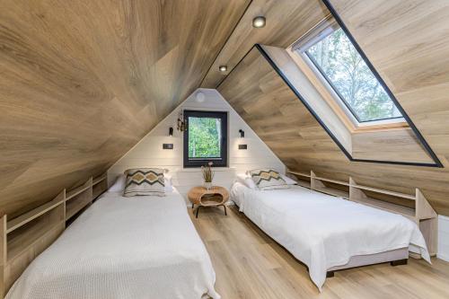 two beds in a attic bedroom with a skylight at CozyEst Meremõisa in Meremõisa