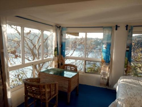 a bedroom with a bed and a desk and windows at The Blue Apartment in Puerto Ángel