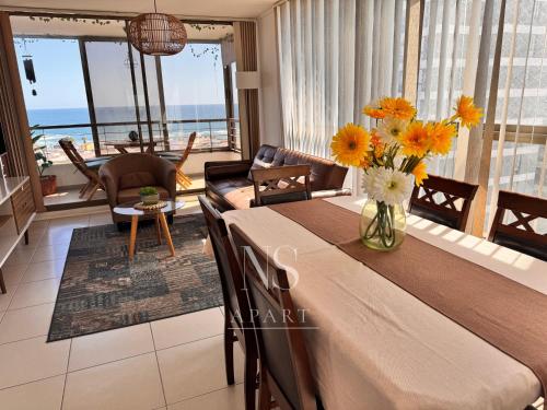 a dining room with a table with a vase of flowers at NORTHSUITE - Vista al Mar - 3 Dormitorios - Parking in Antofagasta