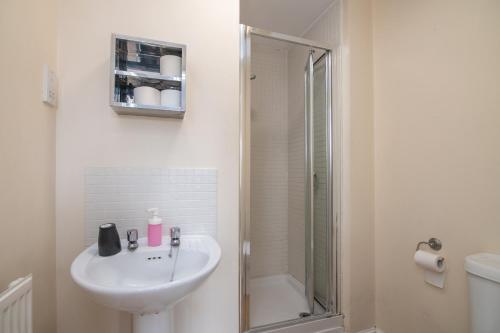 a white bathroom with a sink and a shower at Fantastic 4 bed house with 3 bathrooms in pleasant location in Great Barr