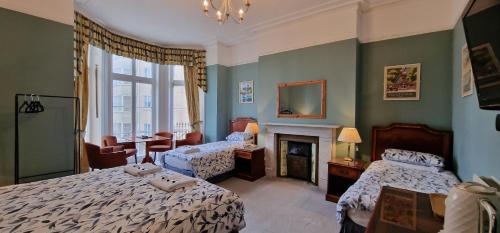 a bedroom with two beds and a fireplace at The Portland Hotel in Folkestone