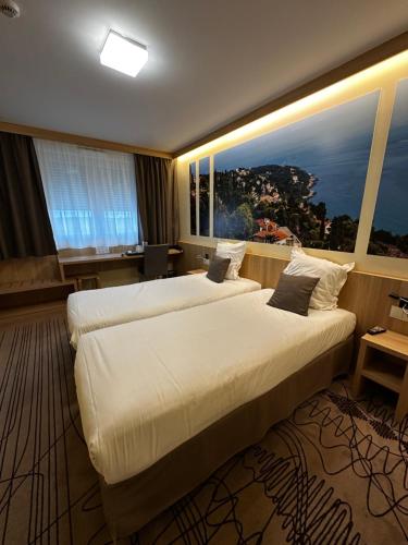 a hotel room with two beds and a large window at Brit Hotel Montargis in Mormant-sur-Vernisson