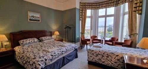 a bedroom with a bed and a desk and a window at The Portland Hotel in Folkestone