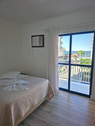 a bedroom with a bed and a view of a balcony at Oceano Hotel de Barra Velha in Barra Velha