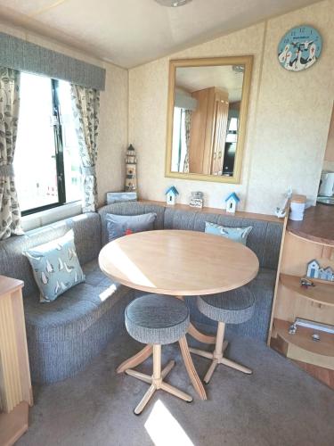 a living room with a table and a couch at VJ Plum a 2 bed 6 berth luxury static caravan, bedding Included, on Coral Beach in Ingoldmells in Ingoldmells