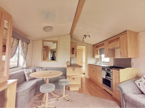 a small kitchen and living room with a table in a caravan at VJ Plum a 2 bed 6 berth luxury static caravan, bedding Included, on Coral Beach in Ingoldmells in Ingoldmells
