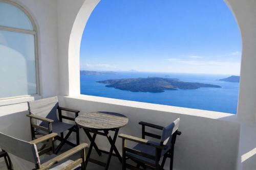 a table and chairs on a balcony with a view of the ocean at Yposkafo Suites - Private Studio - Santorini in Fira