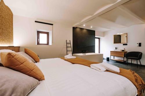 a bedroom with a large white bed with a desk at Gîte Grise Pierre in Herve