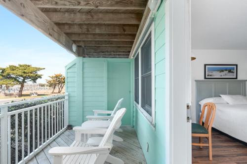 a room with a bed and chairs on a balcony at The Ocracoke Harbor Inn in Ocracoke