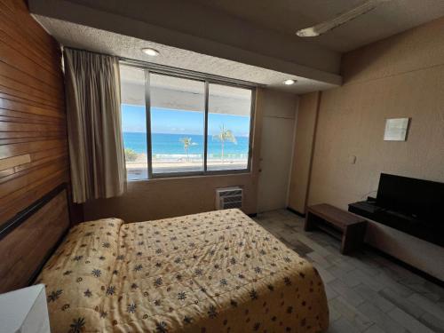a bedroom with a bed and a view of the beach at Hotel De Cima Beach Club in Mazatlán
