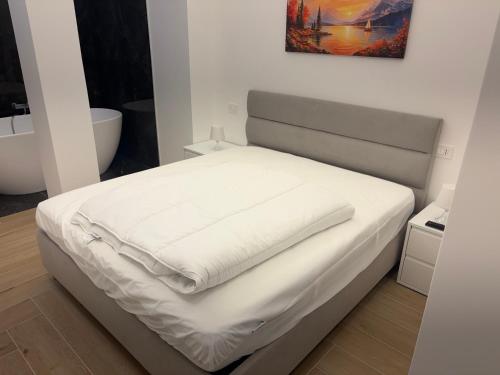 a bed with white sheets on it in a room at Bilocale accogliente in centro Aprica in Aprica