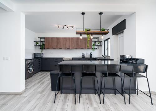 a kitchen with black cabinets and a kitchen island with bar stools at Villa Garden - 22 Guests - 2 Pools in Albufeira