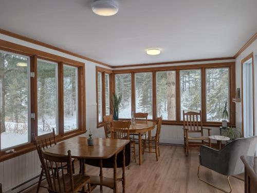 a dining room with tables and chairs and windows at Auberge Baie-St-Paul in Baie-Saint-Paul