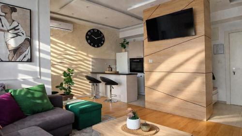a living room with a couch and a clock on a wall at Extra Apartman in Banja Luka