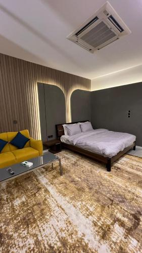 a bedroom with a bed and a yellow couch at محمد هوم in Al Hofuf