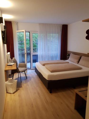 a bedroom with a bed and a desk and windows at Gestütsgasthof Marbach in Marbach