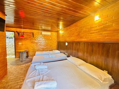 a row of beds in a room with a brick wall at Pousada do Forte in Barra do Cunhau