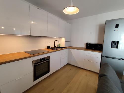 a kitchen with white cabinets and a stainless steel refrigerator at Chez Mika in Linxe