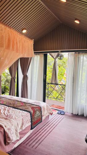 a bedroom with a bed and a large window at Lilys Stone Garden Bungalow in Tram de Dak Mil