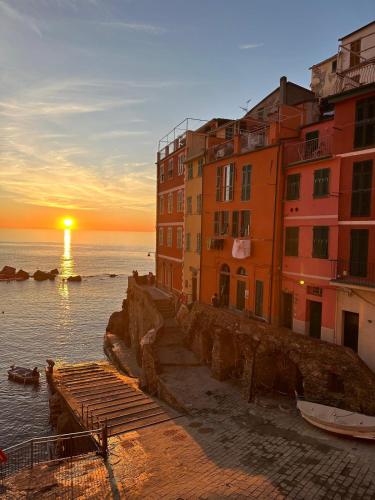 a group of buildings next to the ocean at sunset at Life Class Apartment in Riomaggiore