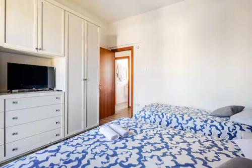 a bedroom with a blue and white bed and a tv at Luminoso Appartamento con Balcone & ParcheggioFree in La Spezia