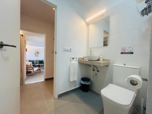 a white bathroom with a toilet and a sink at Smart Apartments Facinas, Piscina y tranquilidad cerca de Tarifa y Bolonia in Facinas
