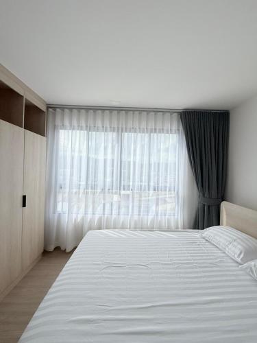 a bedroom with a large white bed and a window at Dcondo Reef kathu Patong in Kathu