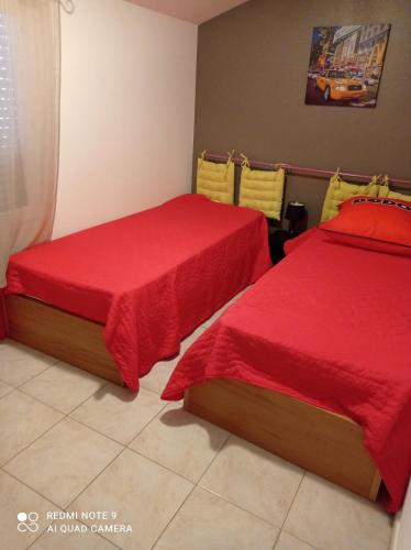 two beds in a room with red sheets at villa Montecristo in Cervione