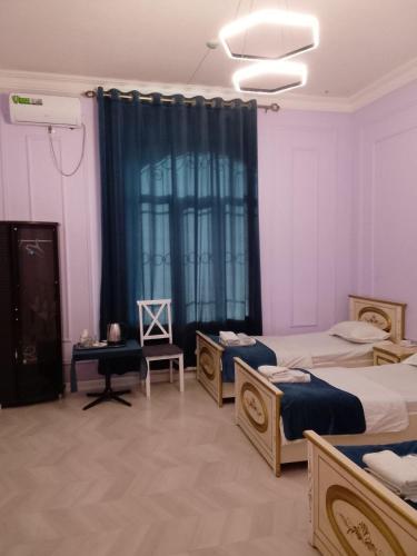 a bedroom with three beds and a blue curtain at Bodomzor Family Hotel in Salor Bekati