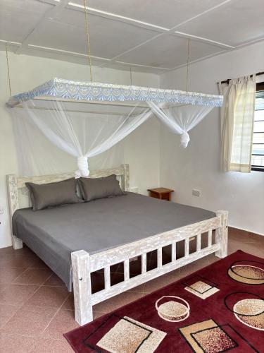 a bedroom with a wooden bed with a canopy at Mango House Watamu in Watamu